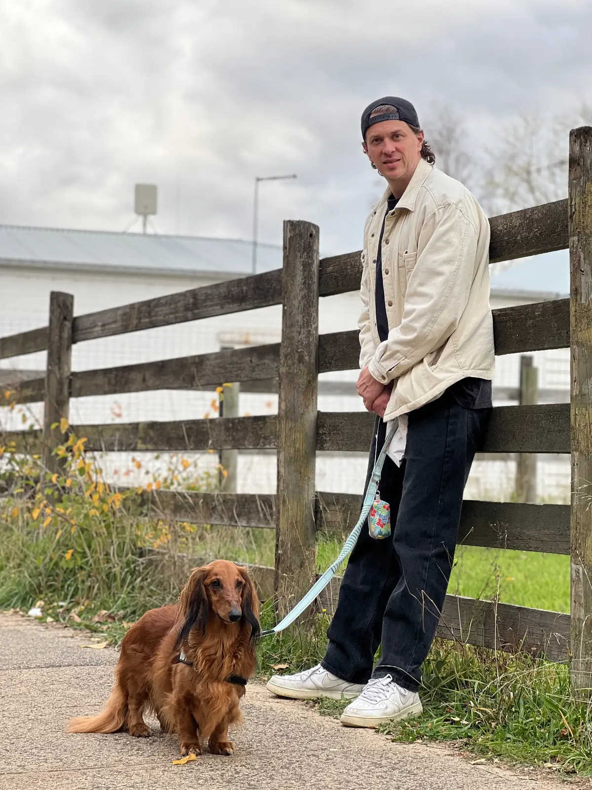 Tazz McAlister standing with his dog beside a wooden fence